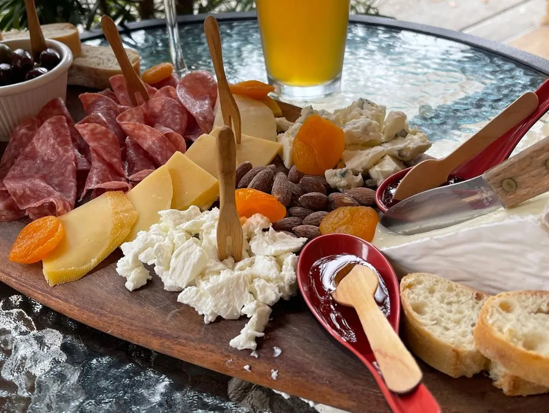 Board 1 charcuterie spread with gouda, brie, soppressata, sliced apple, olives and baguette